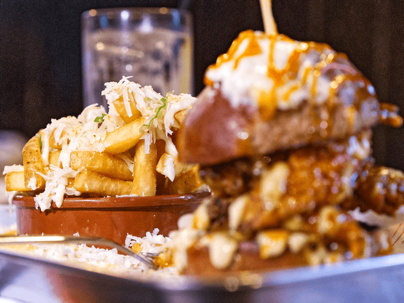 Stacked fried chicken burger with loaded fries, shot for Bun X