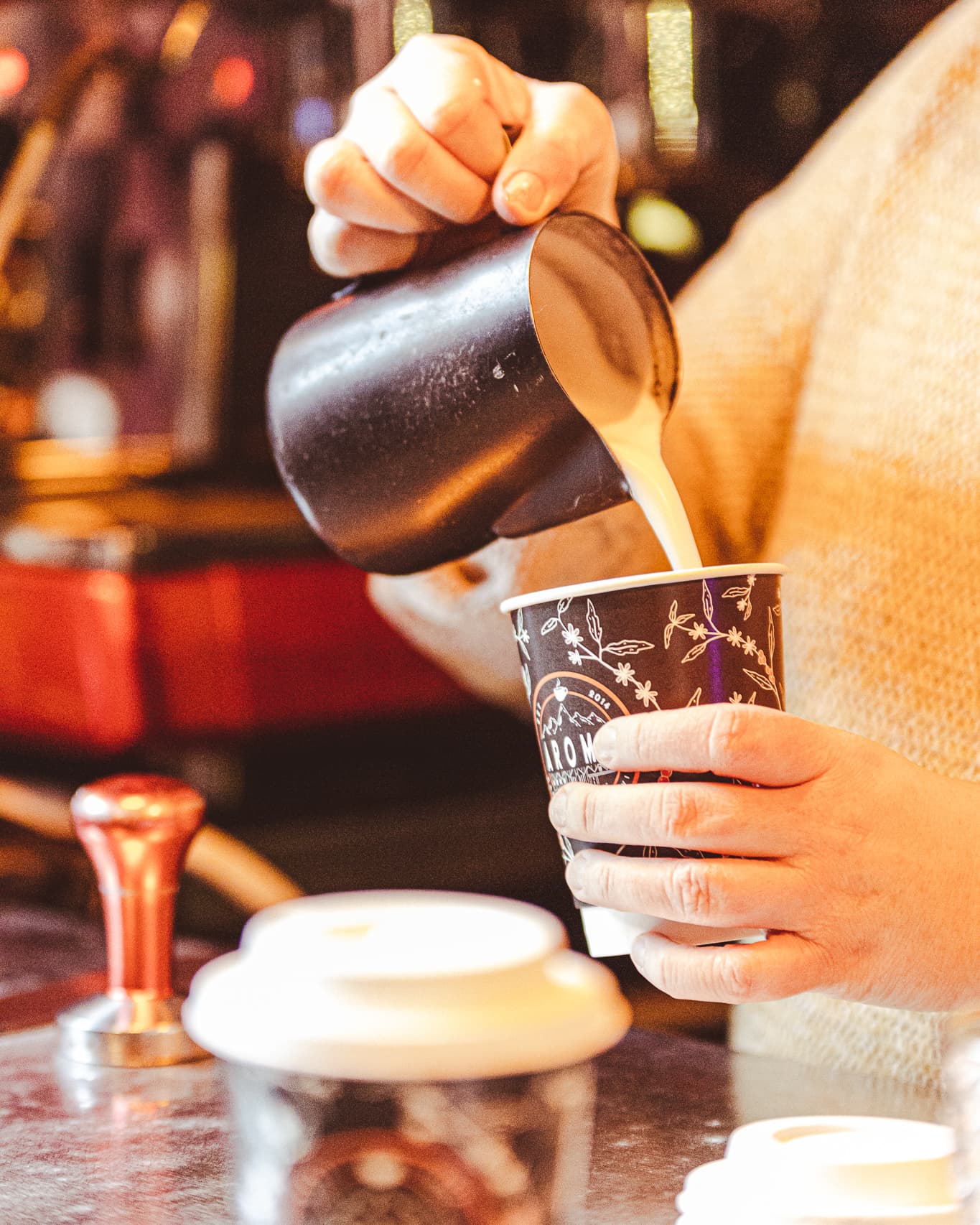 Barista pouring fresh coffee into a takeaway cup at Aroma Norwich