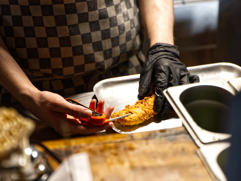Chef wearing black gloves preparing fried food in a commercial kitchen